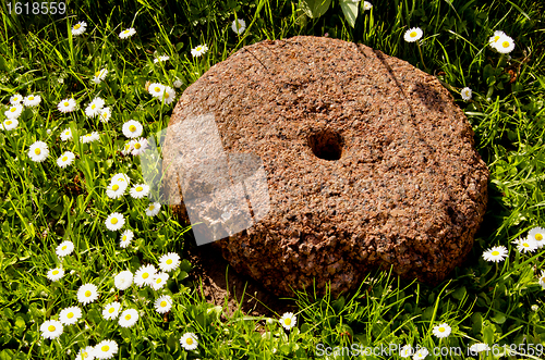 Image of Millstone resting in grass.