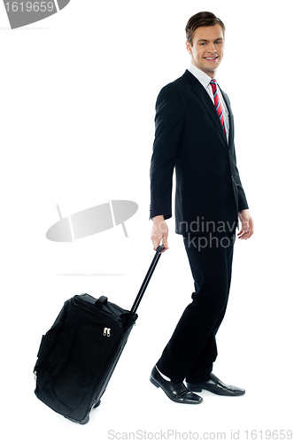 Image of Handsome businessman dragging trolley bag