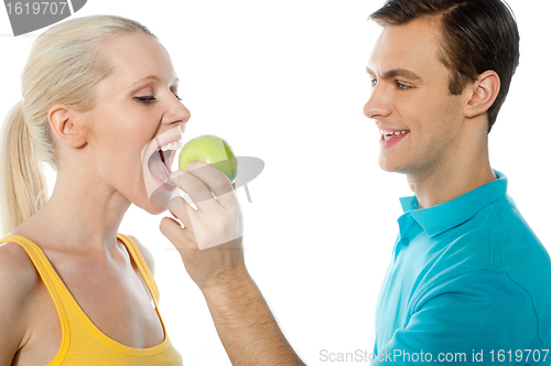 Image of Young guy making her girlfriend eat an apple