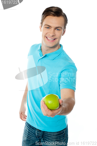 Image of Good looking healthy guy offering a green apple