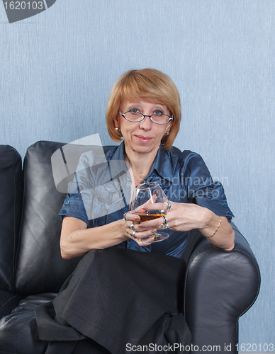 Image of woman with a glass brandy on couch