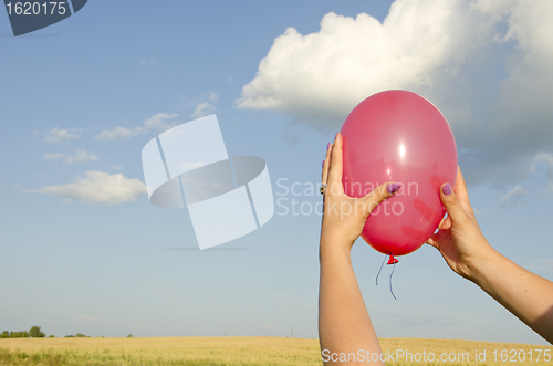 Image of Woman hand hold red balloon background sky field 