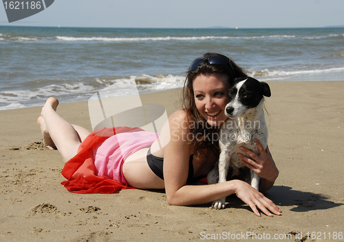 Image of happy woman on the beach with her dog