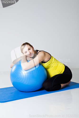 Image of Pregnant woman relaxing against fitness ball