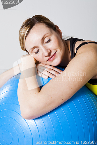 Image of Pregnant woman relaxing against fitness ball