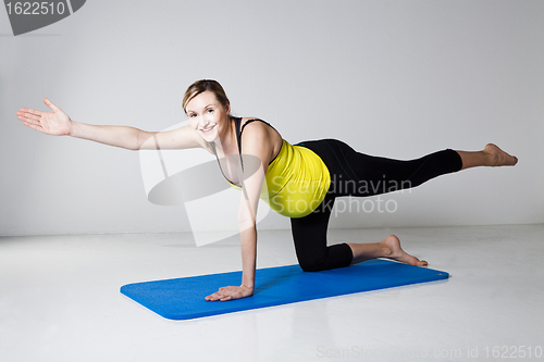 Image of Pregnant woman exercising on mat