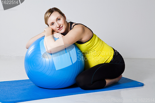 Image of Pregnant woman relaxing against fitness ball