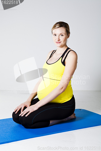 Image of Pregnant woman kneeling on mat