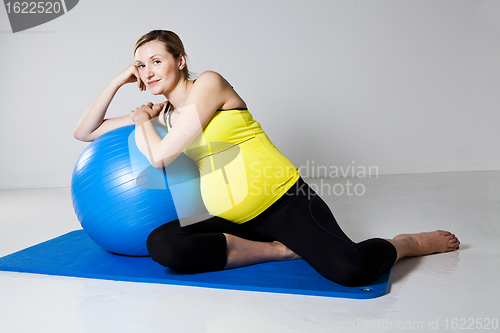 Image of Pregnant woman relaxing against fitness ball