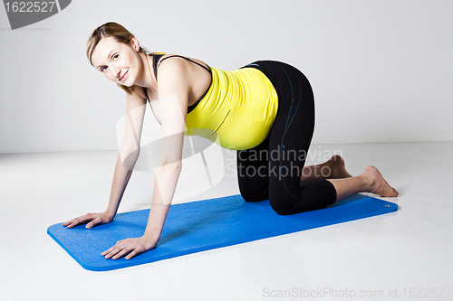 Image of Pregnant woman kneeling on mat