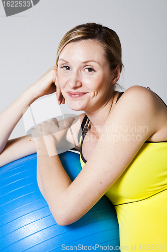 Image of Pregnant woman relaxing against fitness ball