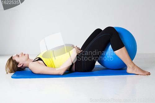 Image of Pregnant woman exercising with fitness ball