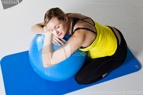 Image of Pregnant woman relaxing against fitness ball