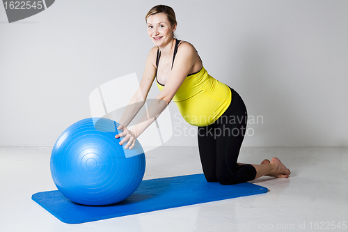 Image of Pregnant woman exercising with fitness ball