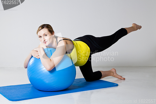 Image of Pregnant woman exercising with fitness ball