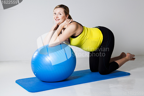 Image of Pregnant woman exercising with fitness ball