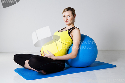 Image of Pregnant woman relaxing against fitness ball