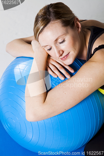 Image of Pregnant woman relaxing against fitness ball