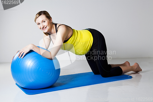 Image of Pregnant woman exercising with fitness ball