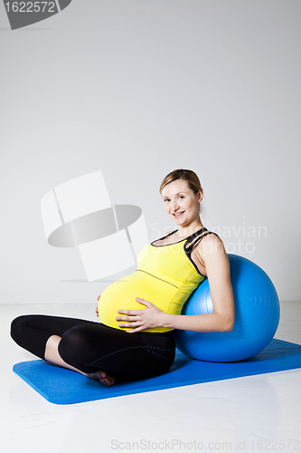 Image of Pregnant woman relaxing against fitness ball