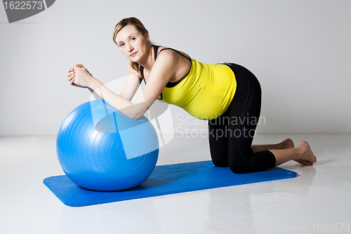 Image of Pregnant woman exercising with fitness ball