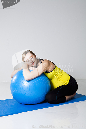 Image of Pregnant woman relaxing against fitness ball