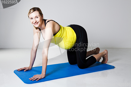 Image of Pregnant woman kneeling on mat