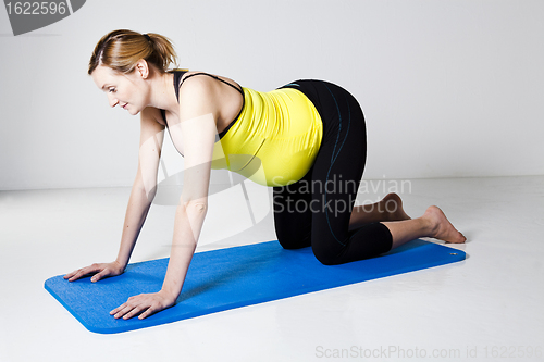 Image of Pregnant woman kneeling on mat