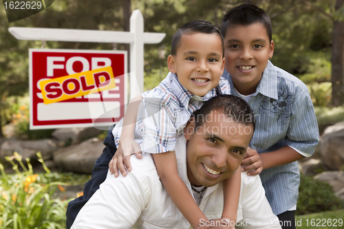 Image of Hispanic Father and Sons in Front of Sold Real Estate Sign