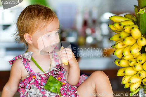 Image of Outdoor portrait of toddler girl with bananas