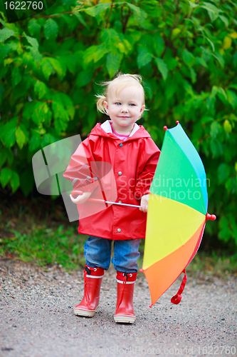 Image of Toddler girl with umbrella outdoors on rainy autumn day