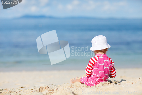 Image of Toddler girl sitting on white sand beach