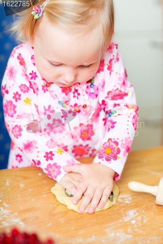 Image of Adorable toddler girl helping at kitchen