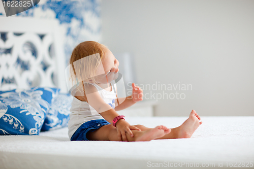 Image of Portrait of playful toddler girl sitting on bed