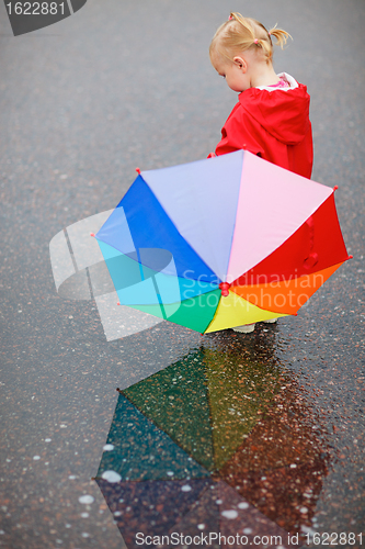 Image of Toddler girl with colorful umbrella on rainy day