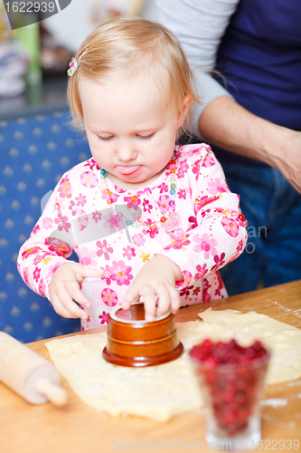 Image of Adorable toddler girl helping at kitchen