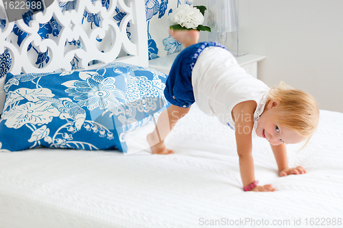 Image of Adorable playful toddler girl in bedroom