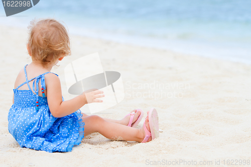 Image of Toddler girl sitting on white sand beach