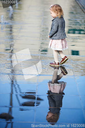 Image of Little girl playing in street fountain