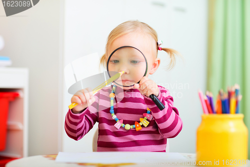 Image of Funny toddler girl playing with magnifier