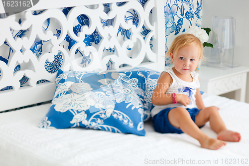 Image of Portrait of toddler girl sitting on bed