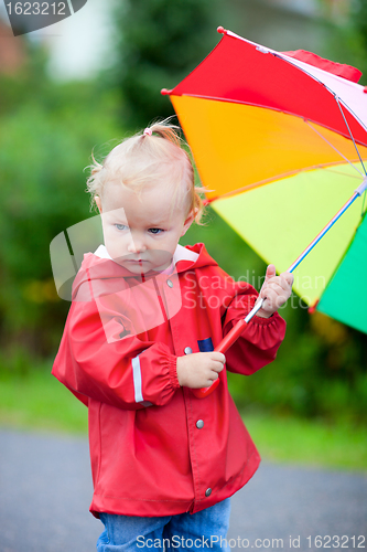 Image of Toddler girl with umbrella outdoors on rainy day