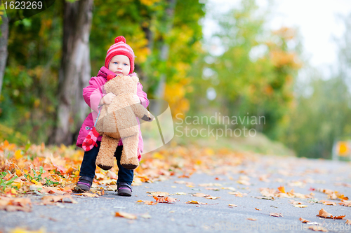 Image of Toddler girl with teddy bear outdoors on autumn day
