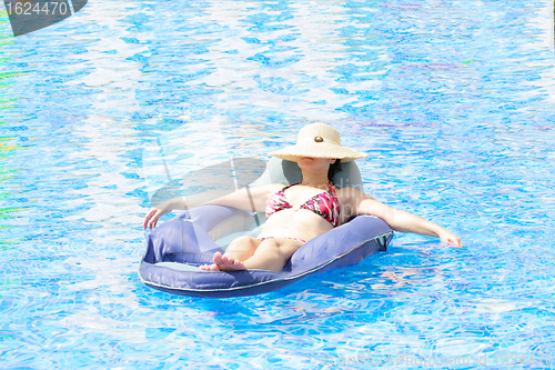 Image of woman resting and tanning in the pool 