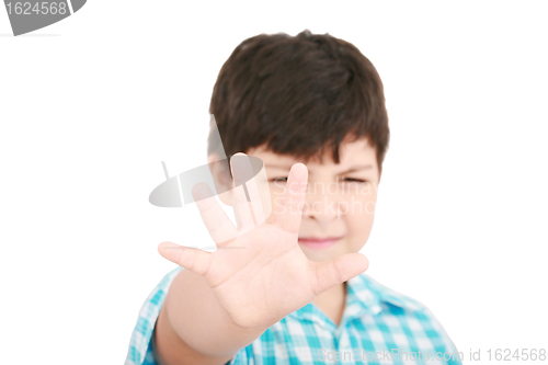 Image of Child looking at camera. Stop signal with his hand.  Boy trying 