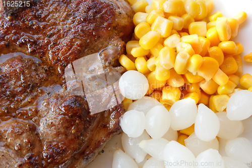 Image of grilled pork steak with corn and small onions