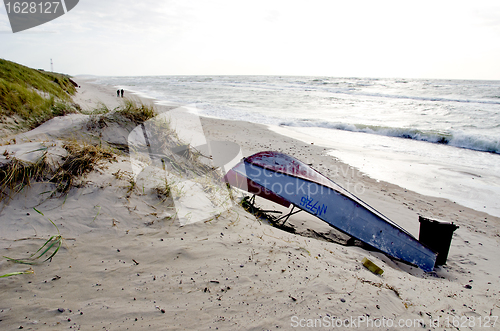 Image of rusty boat lie on sea sand dunes beach people walk 