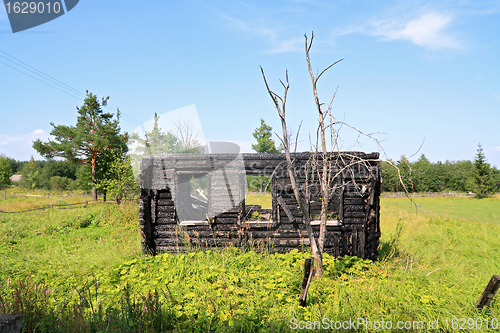 Image of burned house on green field