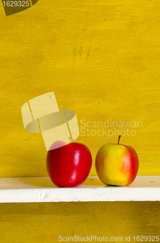 Image of Apples on white shelve yellow wall background. 