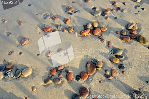Image of Colorful wet pebbles rubed by waves in sea sand. 